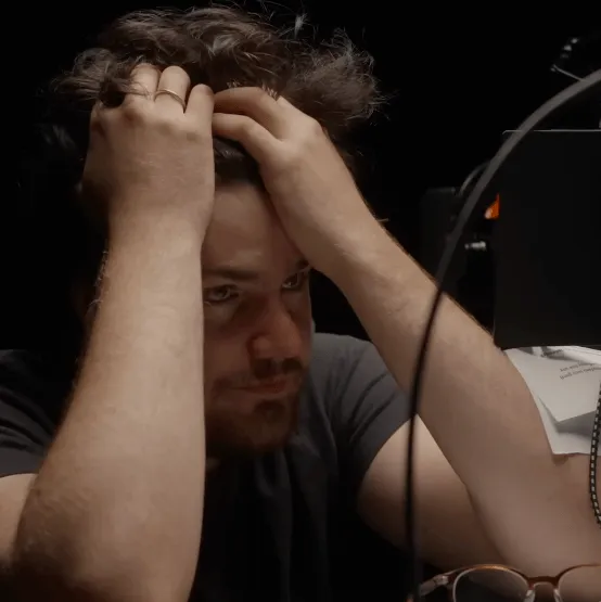 A man sitting at a desk with his hands in his hair, looking troubled.